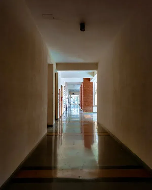 Clean hallway with polished floors, white walls, and natural light streaming through doorways leading to classrooms