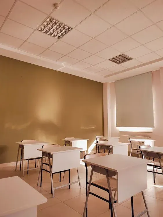 Modern lecture hall with black chairs, whiteboard projection screen, professional lighting equipment, and tiered seating