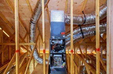 HVAC system in a wooden framed attic with silver ducts.