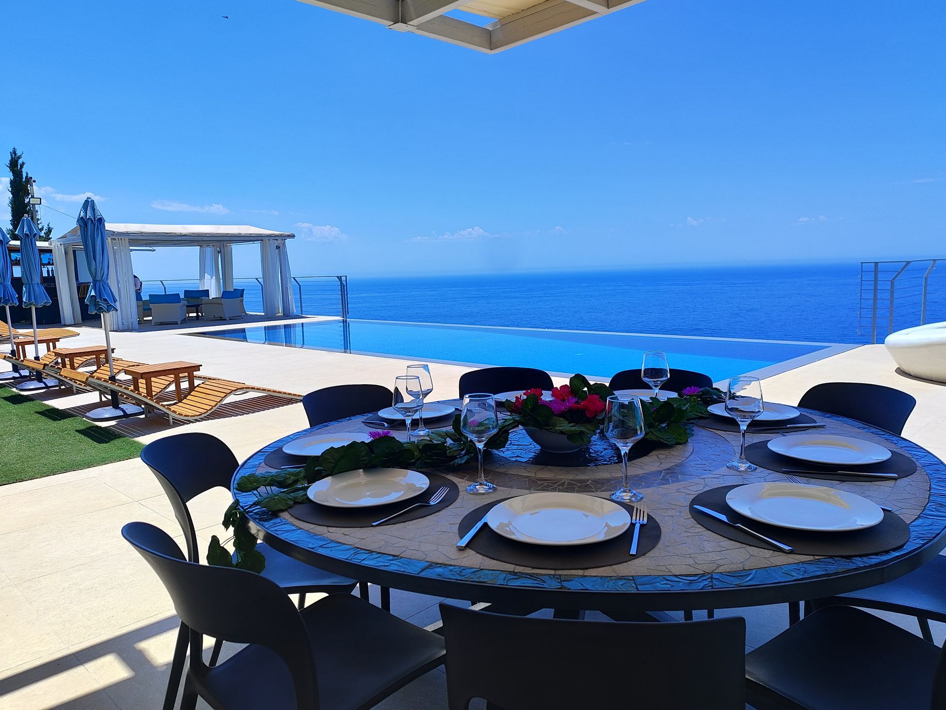 Poolside terrace with wine glasses and bottle overlooking the ocean