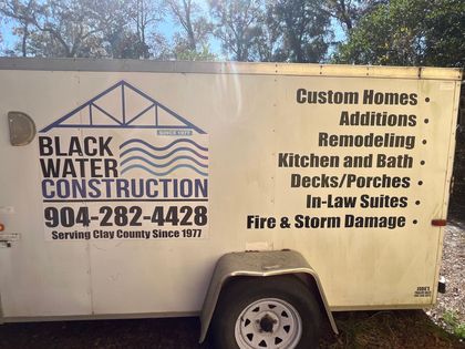 White Black Water Construction trailer with logo, phone number, and listed services on the side
