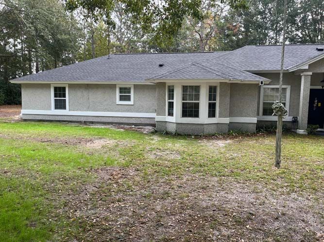 Single-story gray house with a front porch and trees in the yard