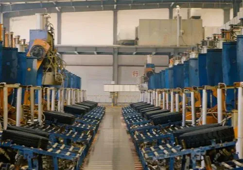 Piso de fábrica con filas de equipos industriales, en su mayoría azules, con brazos automatizados y cintas transportadoras.