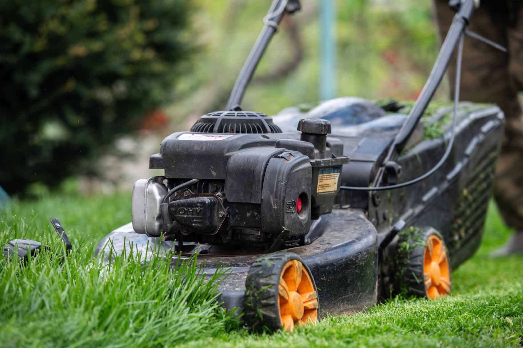 A person is mowing a lush green lawn with a lawn mower.