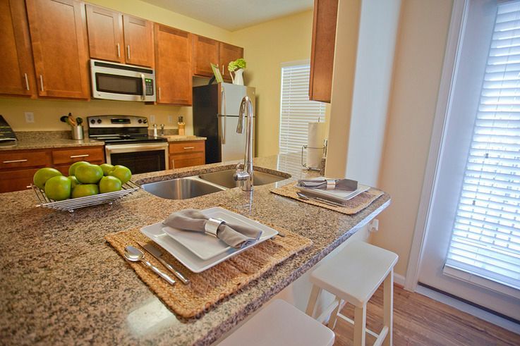 A kitchen with a granite counter top and a bowl of apples on it.