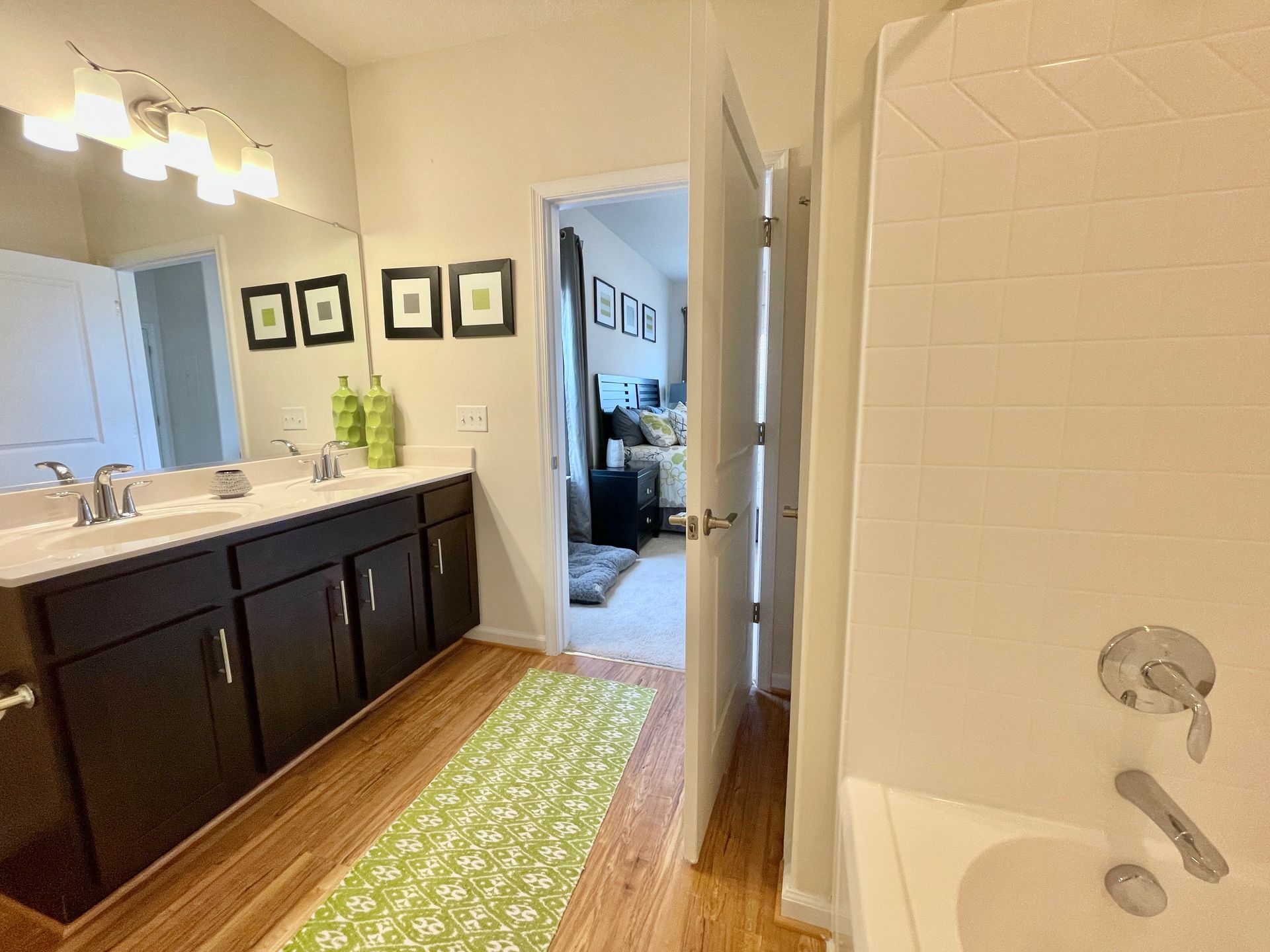 A bathroom with two sinks , a tub , and a mirror.