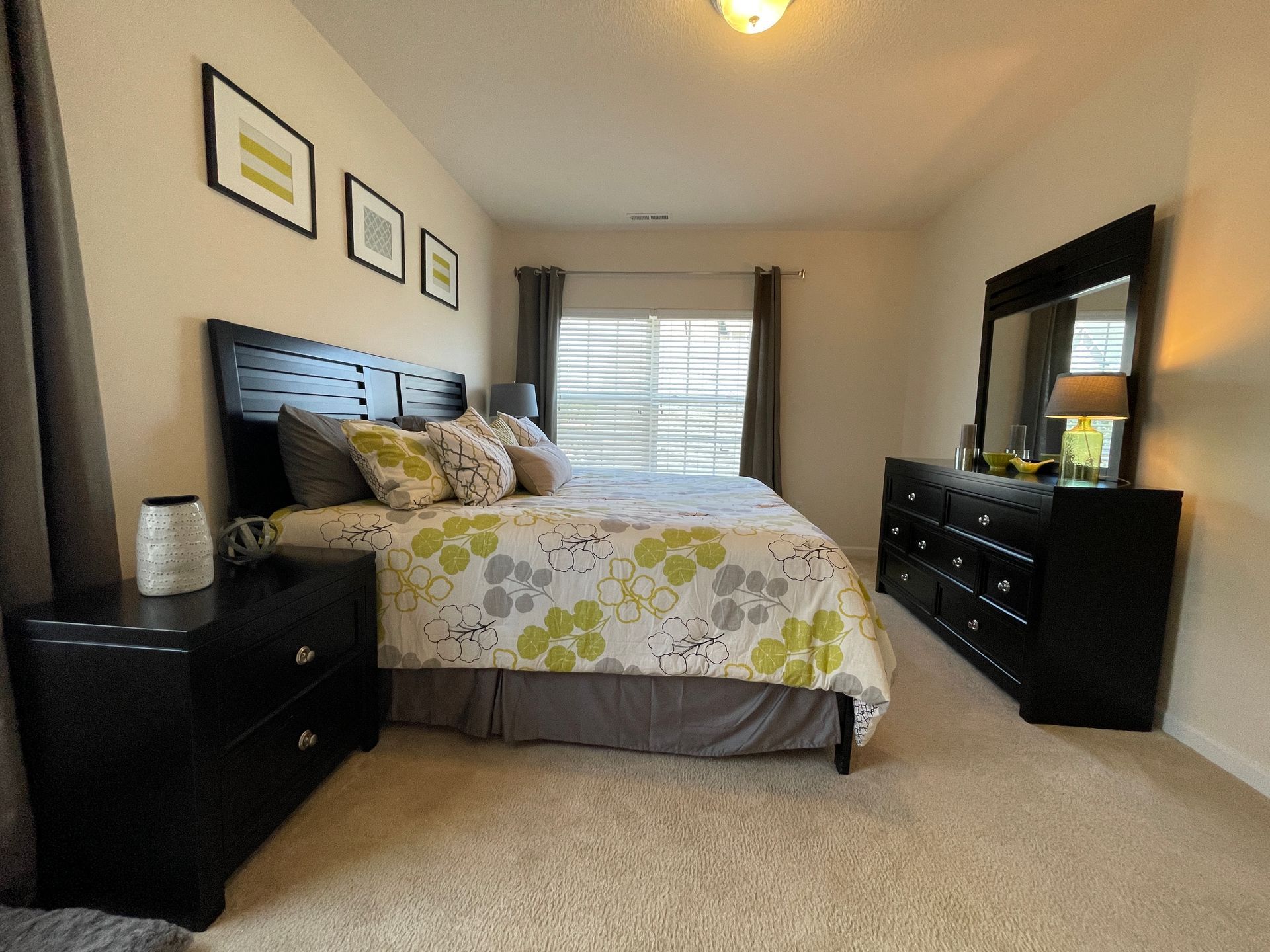 A bedroom with a large bed dresser and mirror