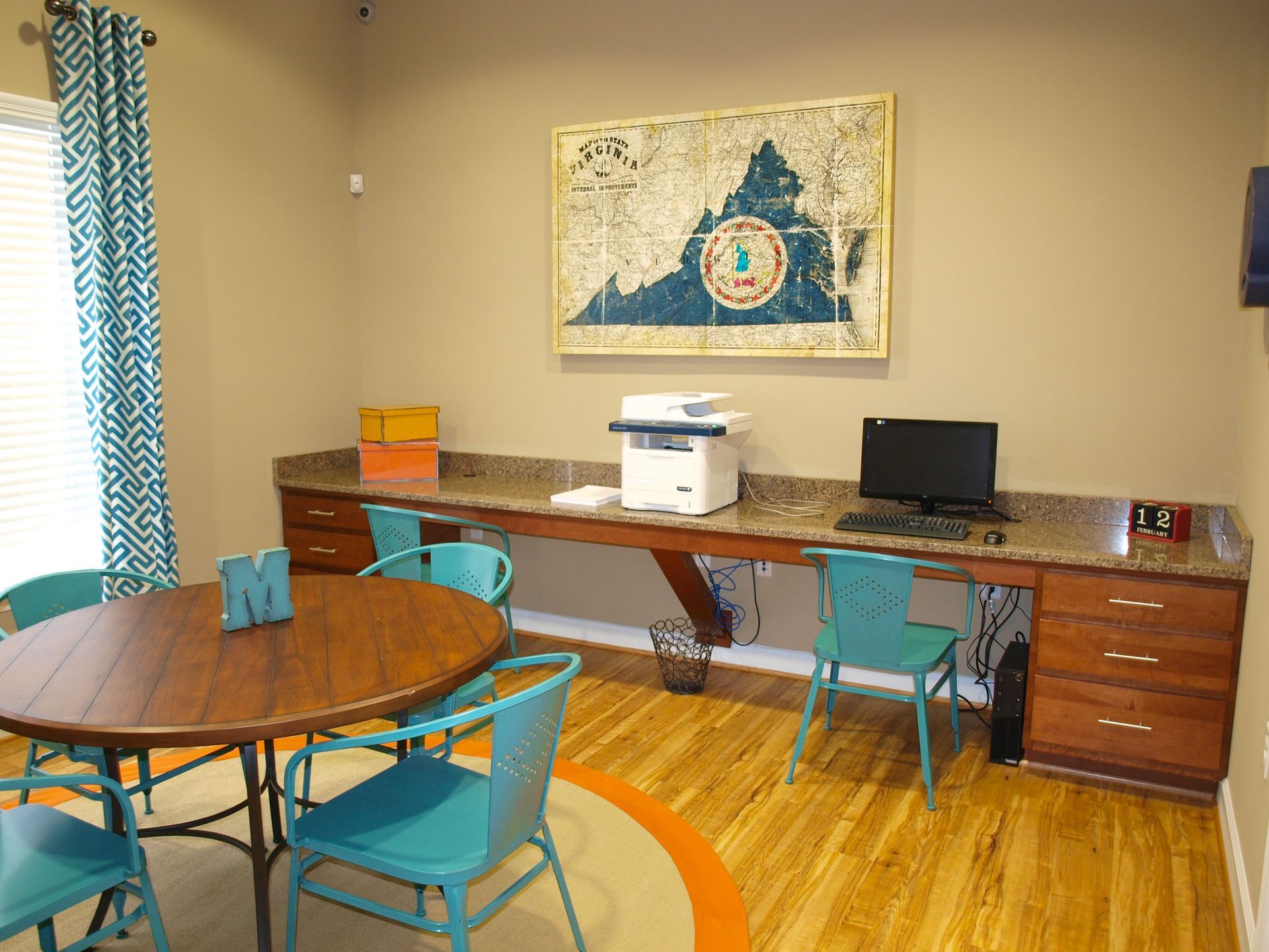 A room with a table , chairs , a computer and a printer.