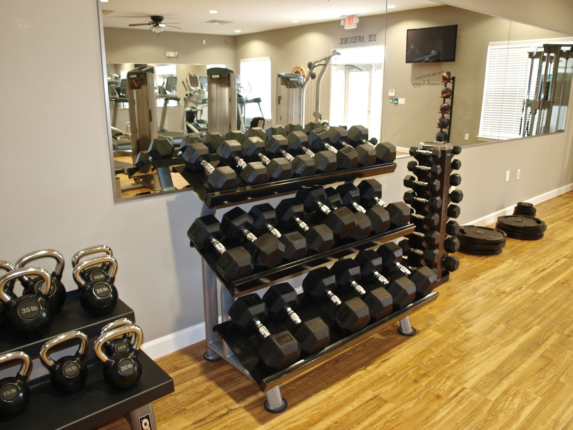 A gym with a lot of dumbbells and kettlebells