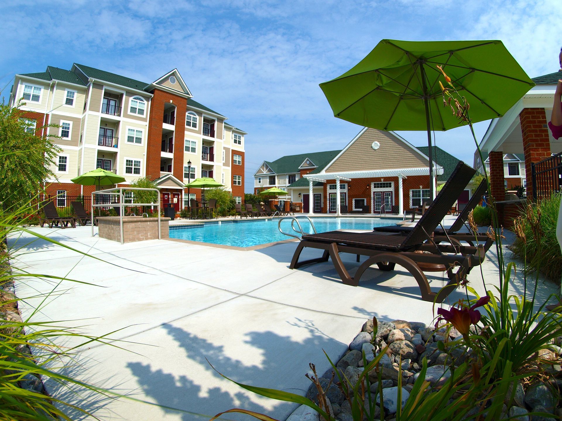 A swimming pool with a green umbrella in front of a building