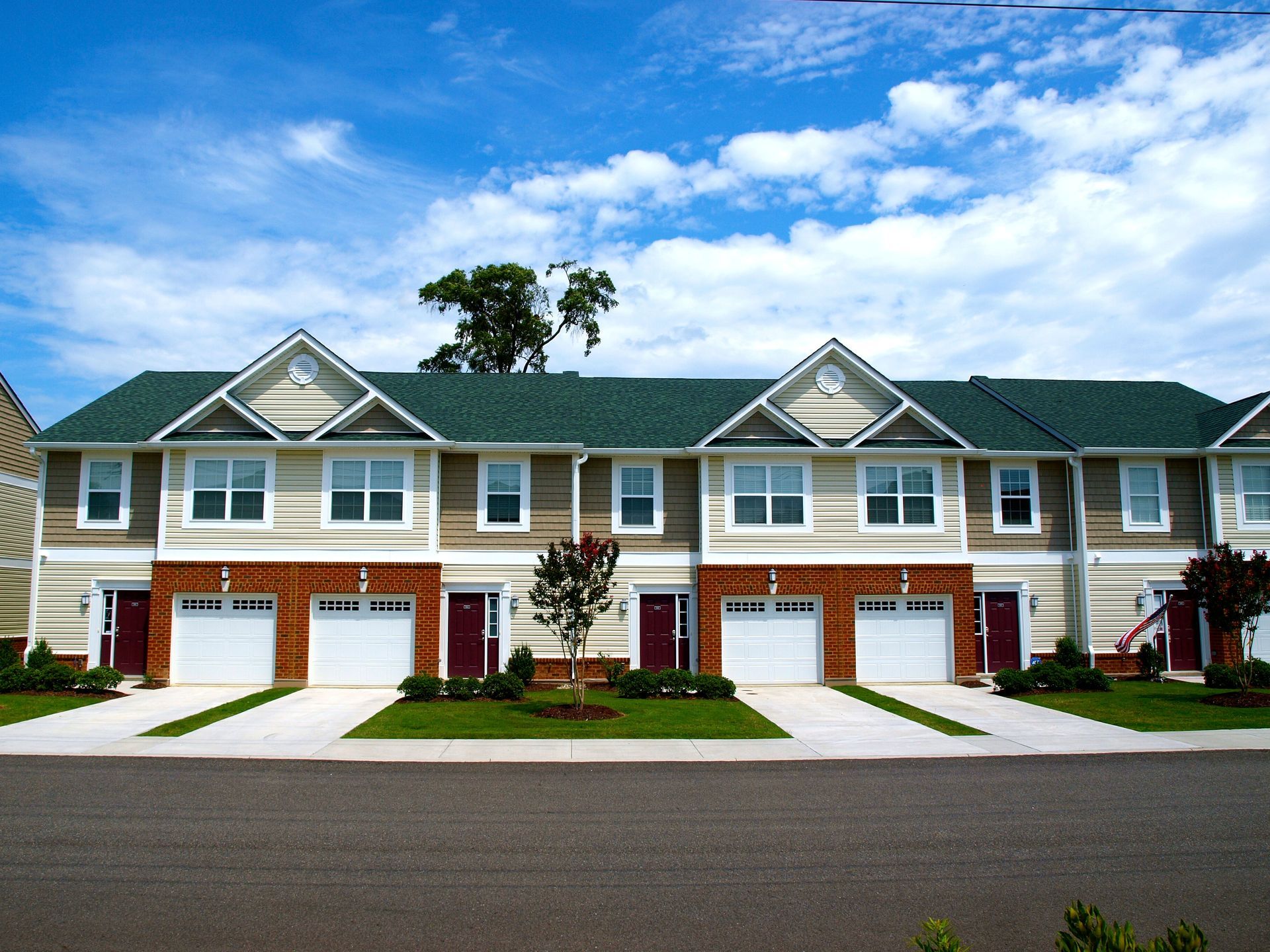 A row of houses with green roofs and white garage doors