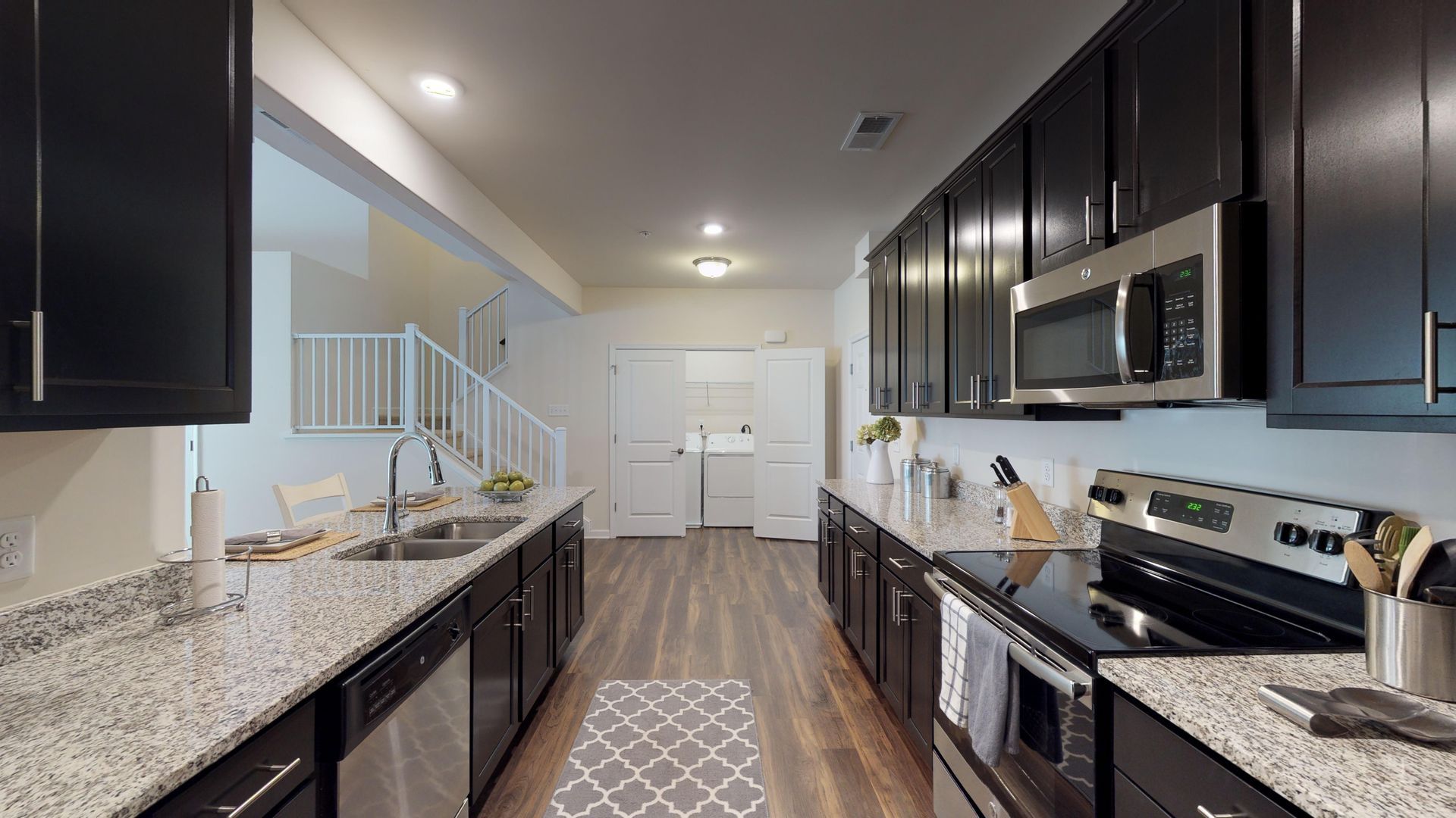 A kitchen with black cabinets , granite counter tops , stainless steel appliances and a stove.