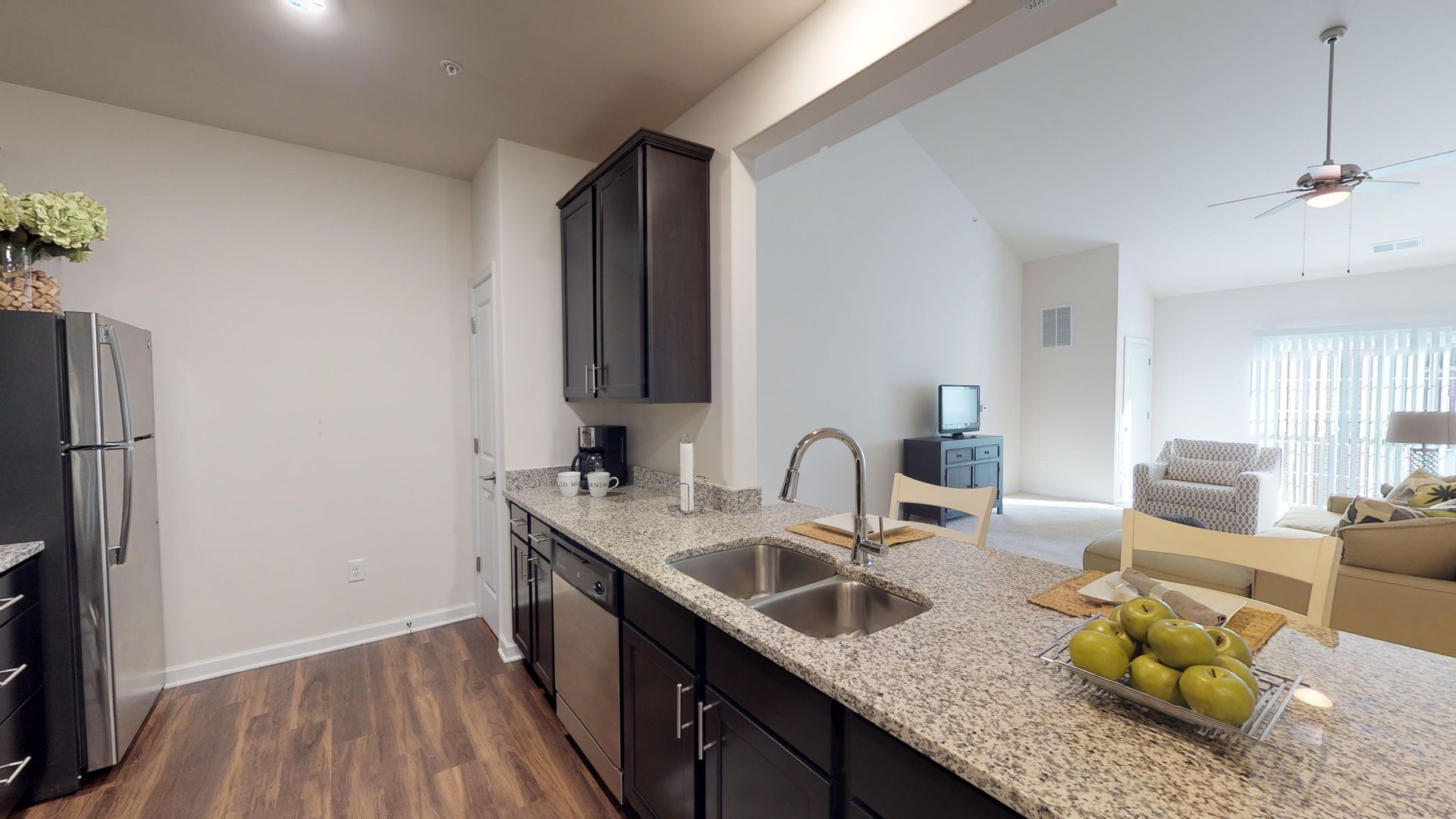 A kitchen with granite counter tops , stainless steel appliances , a sink and a refrigerator.