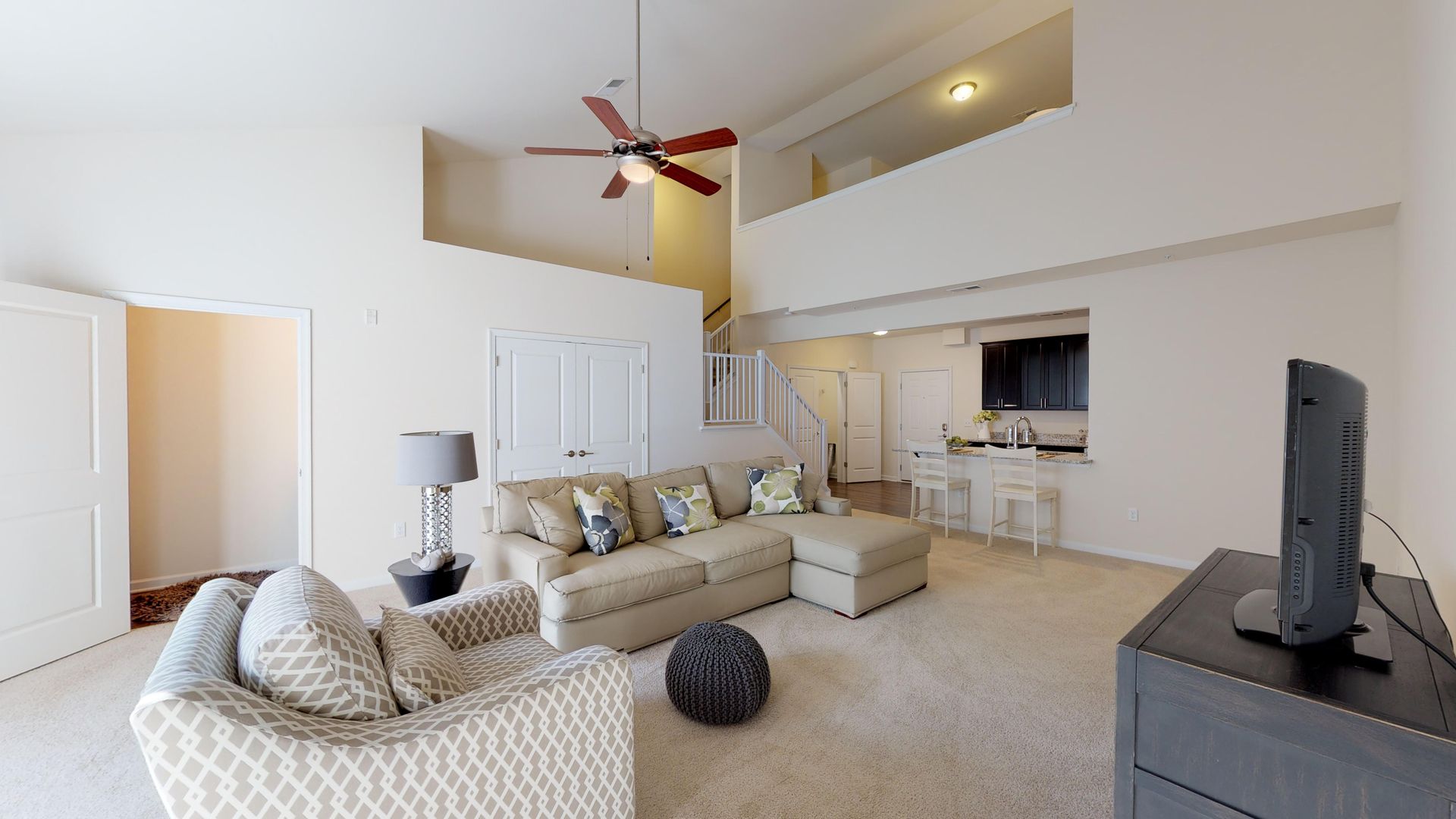 A living room with a couch , chair , television and ceiling fan.