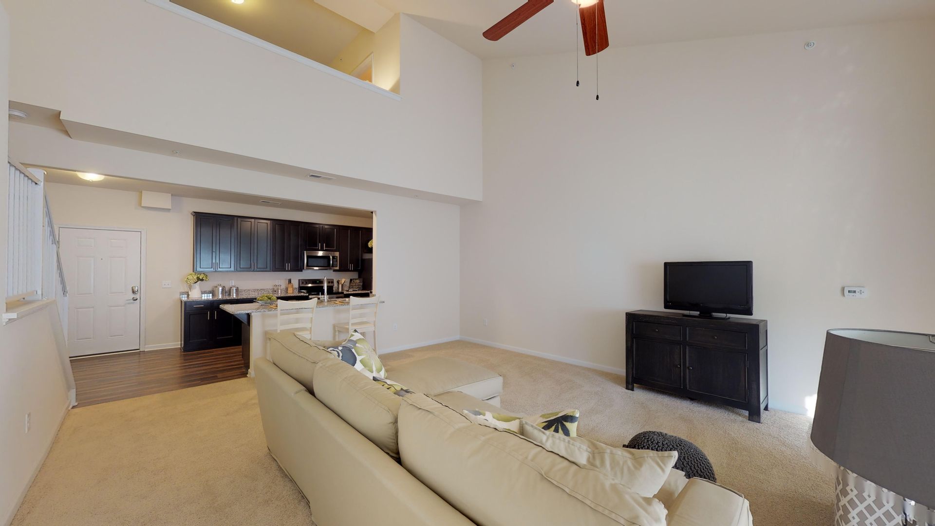 A living room with a couch , television , and ceiling fan.