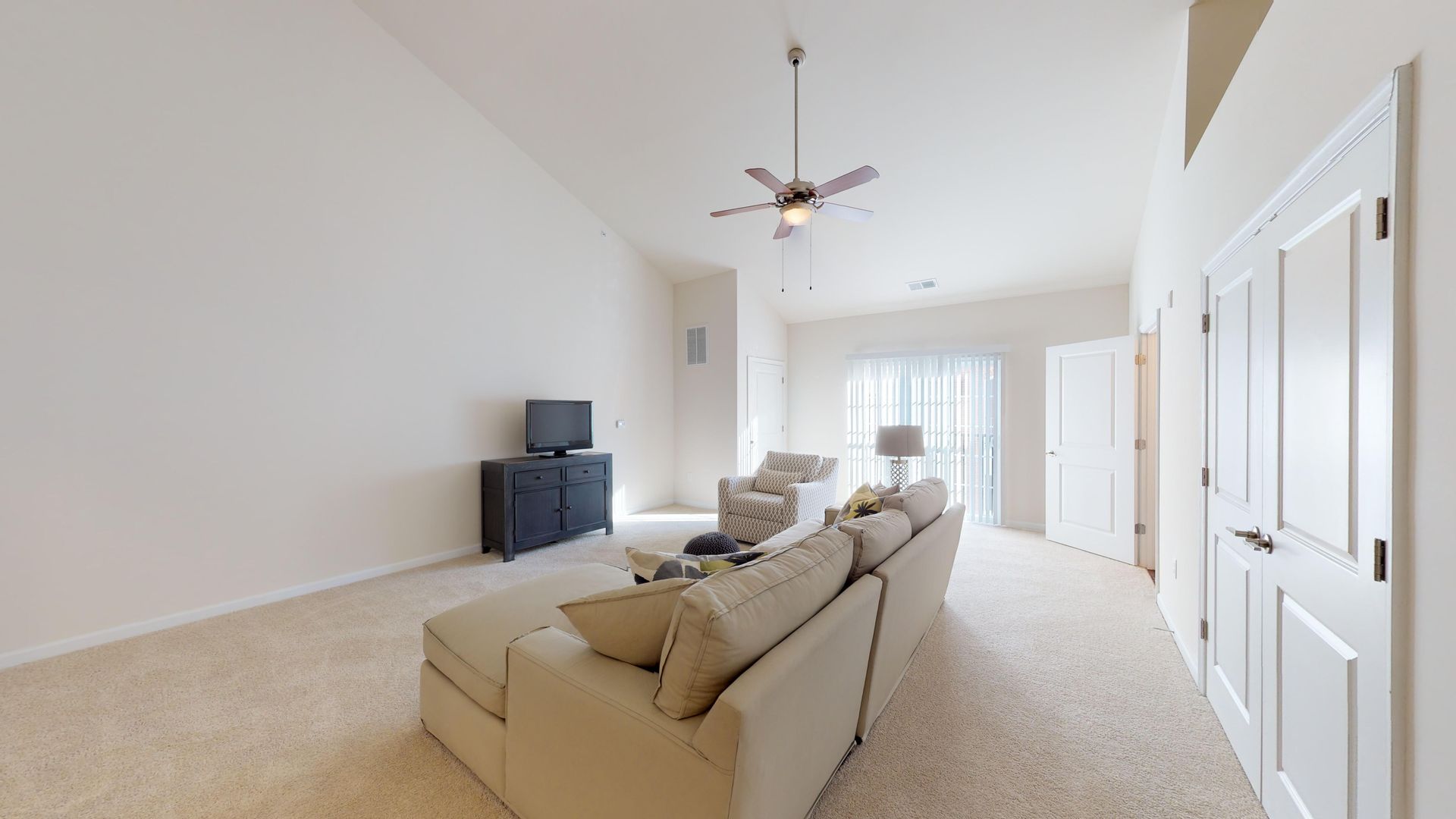 A living room with a couch , television , and ceiling fan.