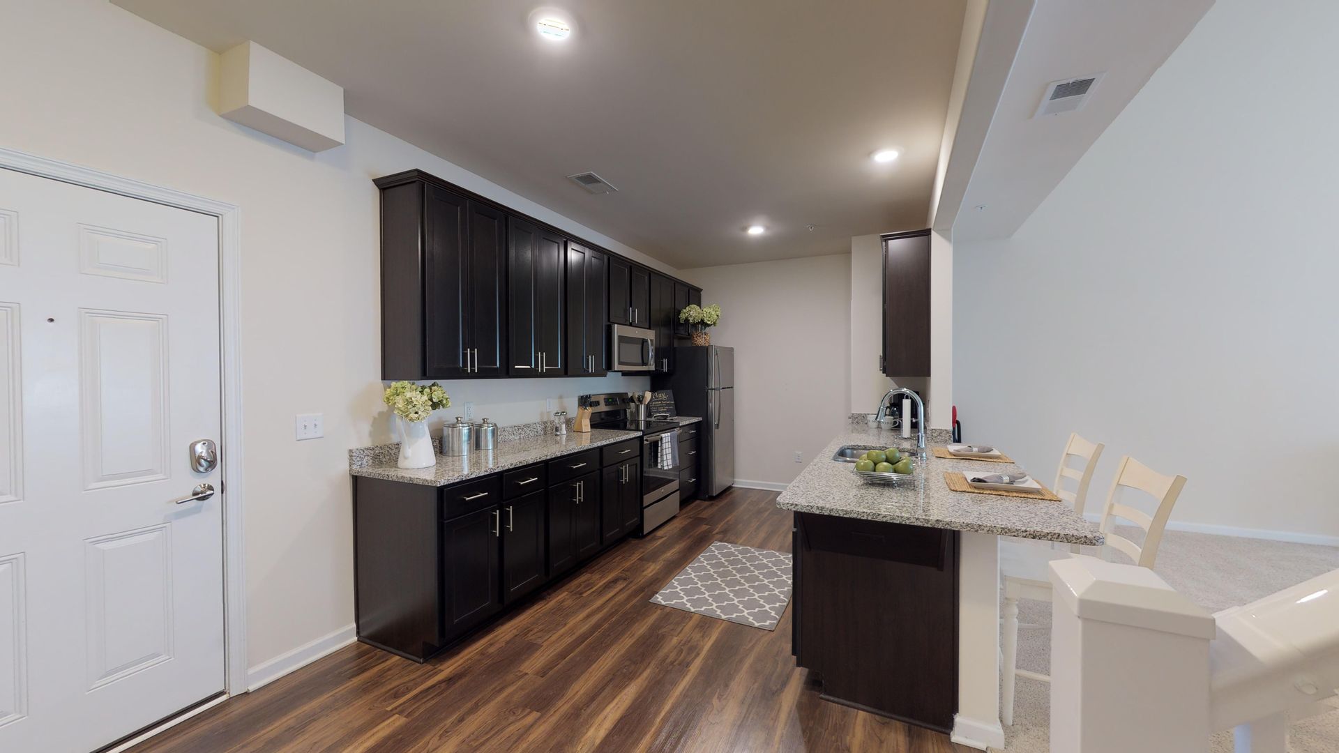 A kitchen with black cabinets , granite counter tops and stainless steel appliances.
