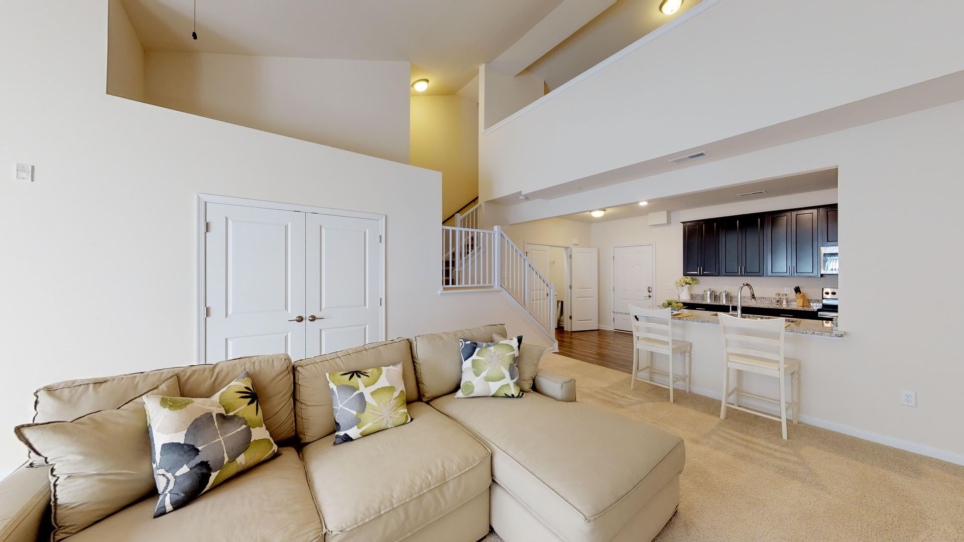 A living room with a couch and a kitchen in the background.