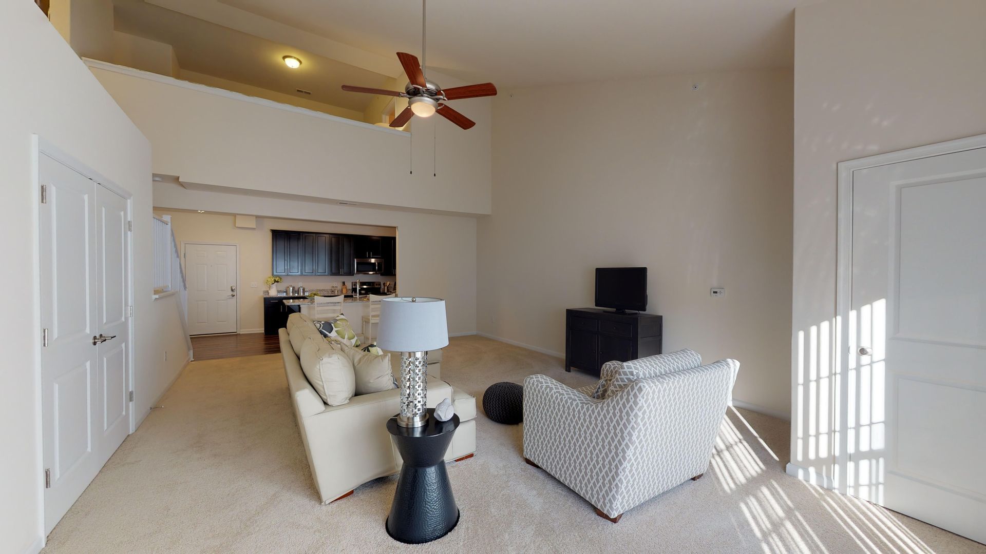 A living room with a couch , chair , lamp and ceiling fan.