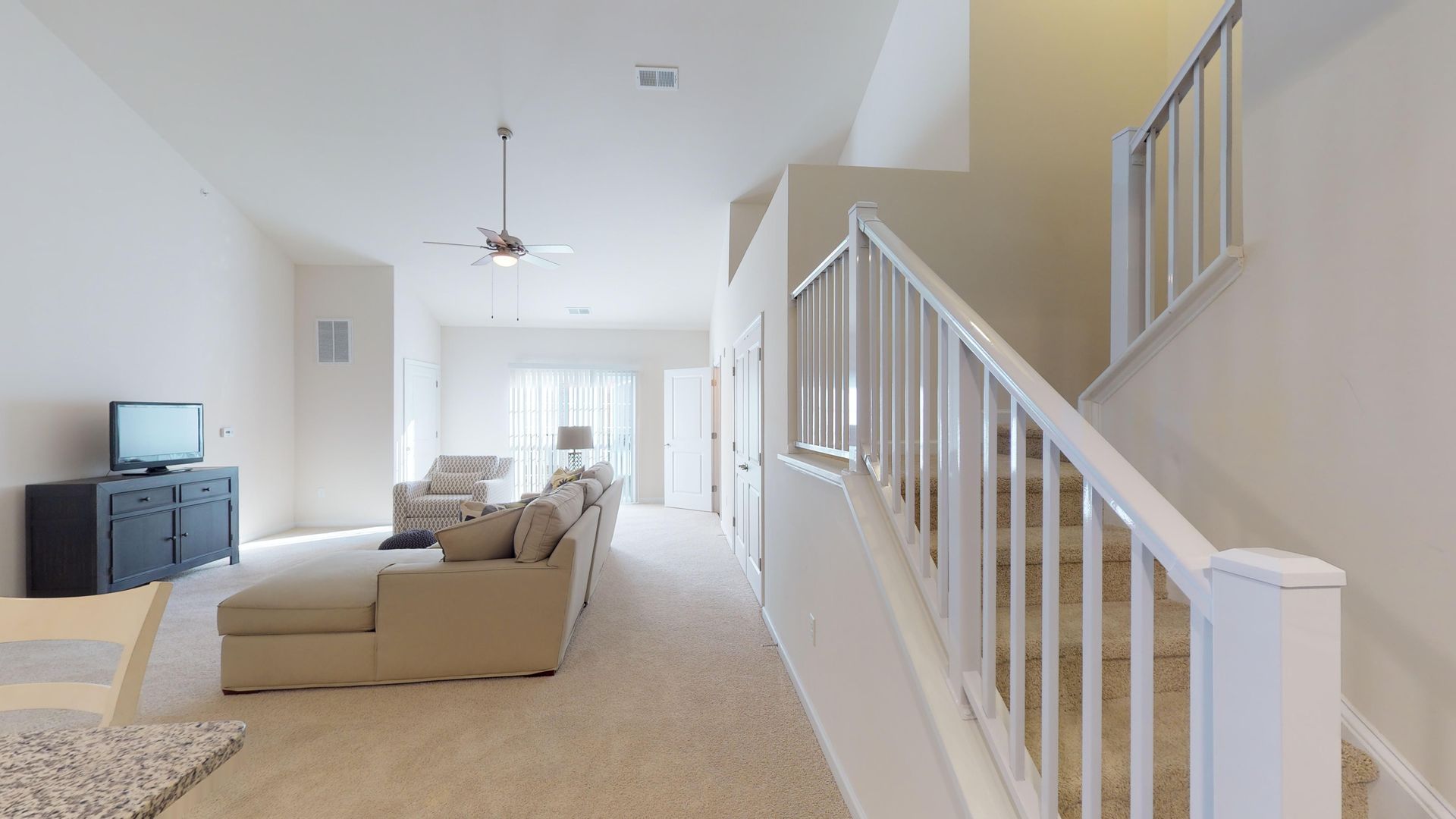 A living room with a couch and stairs leading up to the second floor.