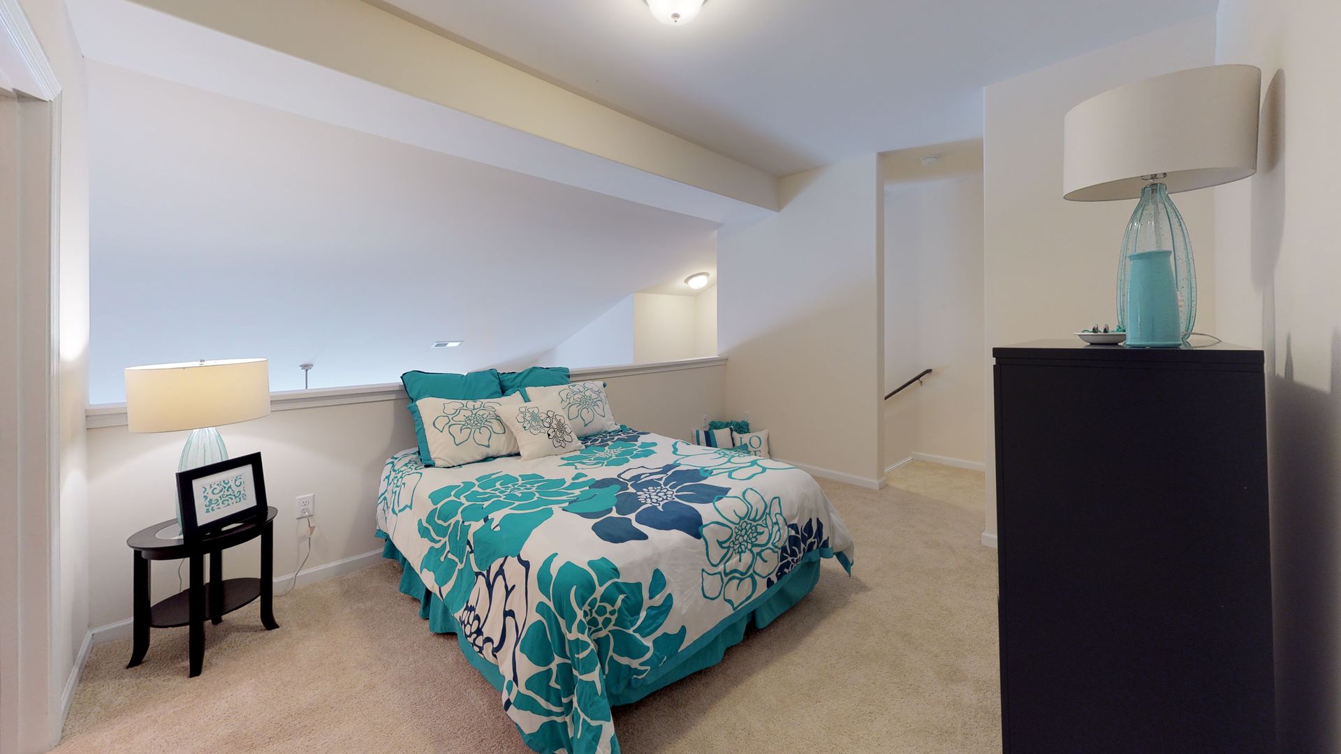 A bedroom with a bed , dresser , lamp and chair.