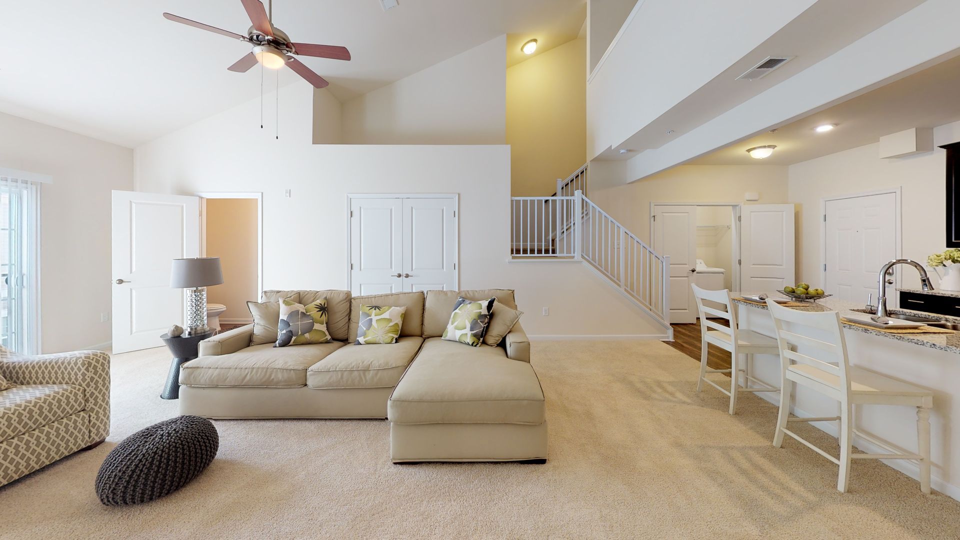 A living room with a couch , chairs , and a ceiling fan.
