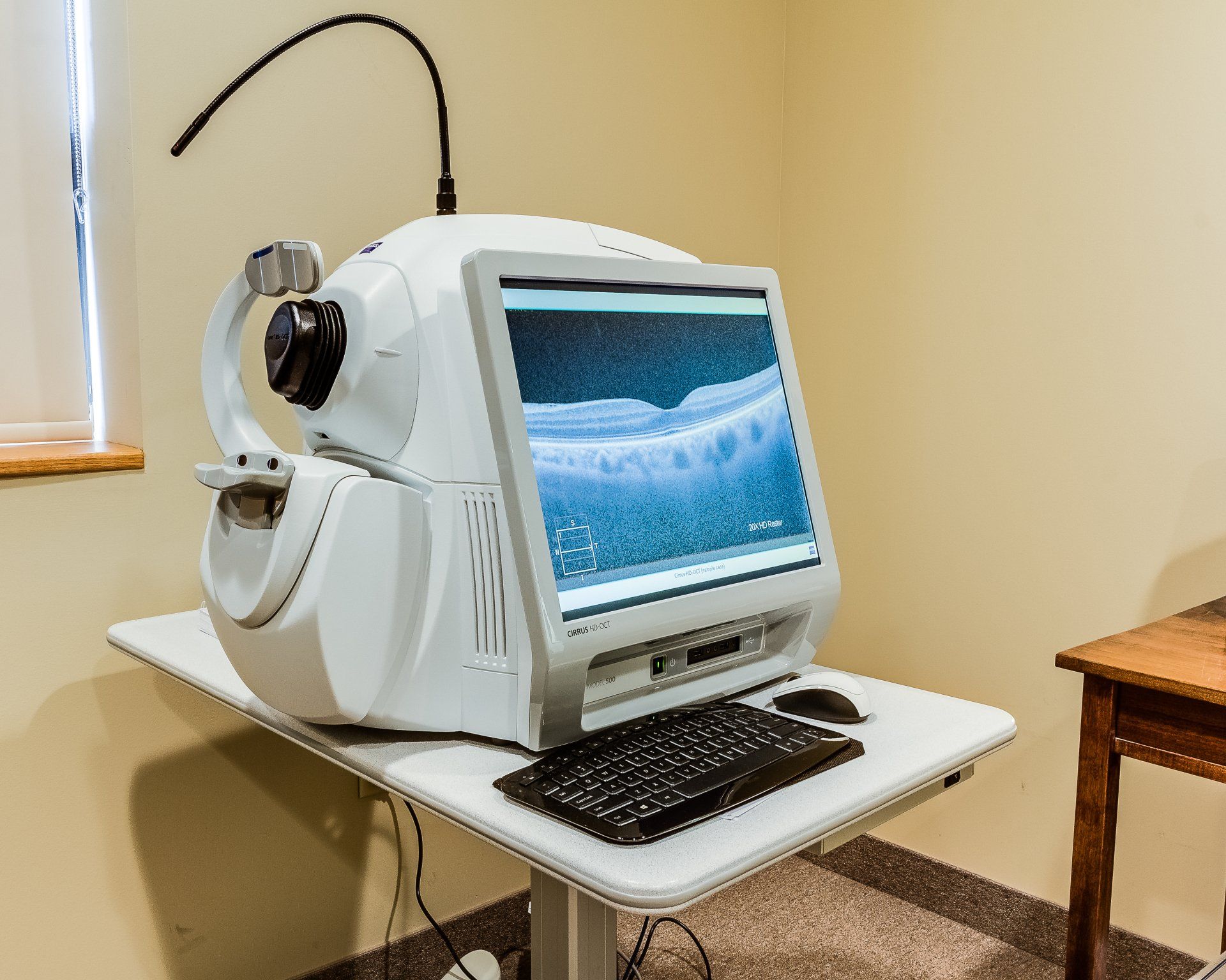 A computer is sitting on a table in a room next to a window.