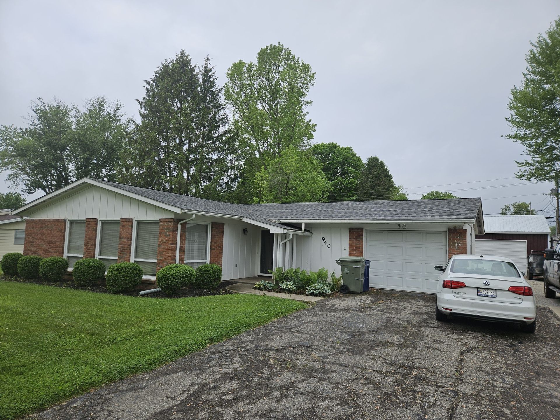 Ranch-style house with brick and white siding, attached garage, and a car parked in the driveway.
