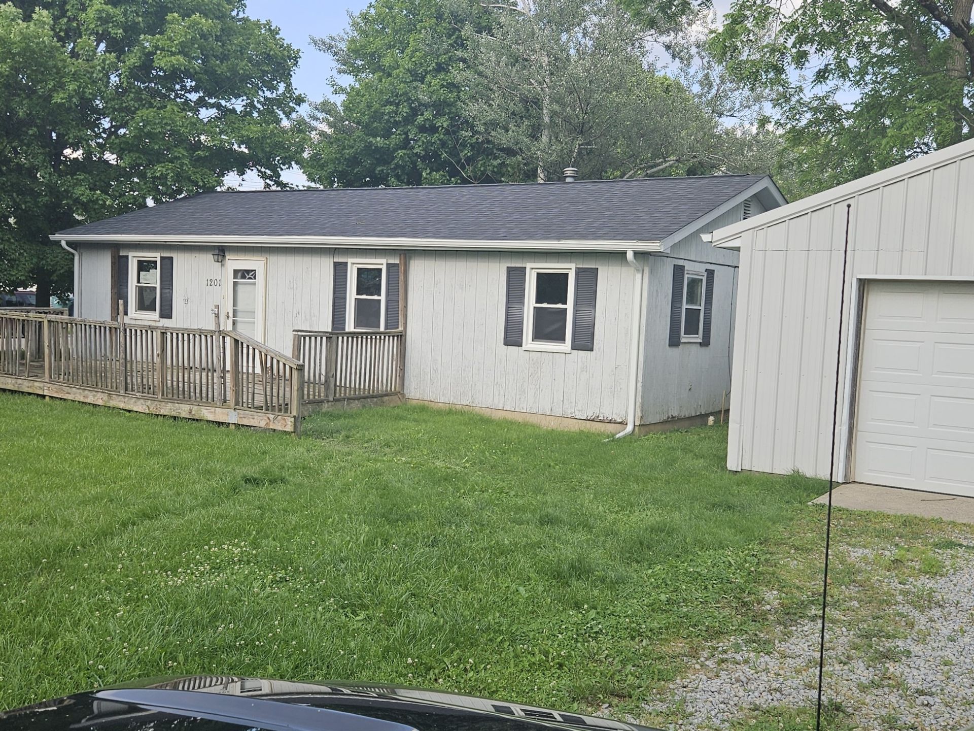 Ranch-style house with a wooden ramp, a detached garage, and a green lawn.