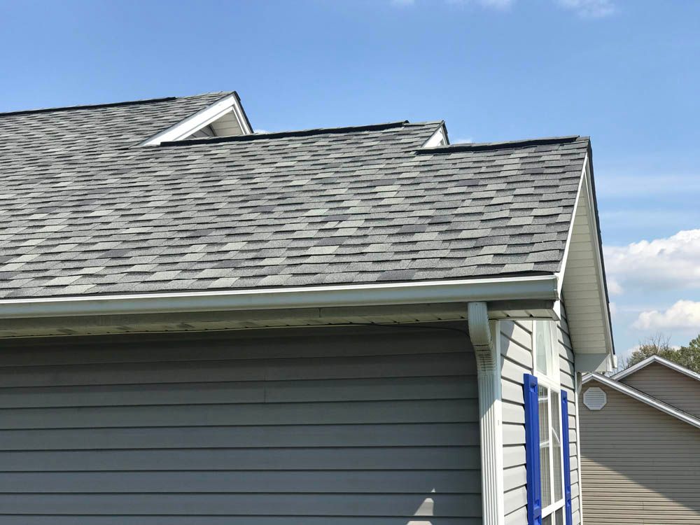Gray shingled roof with white trim and blue sky.