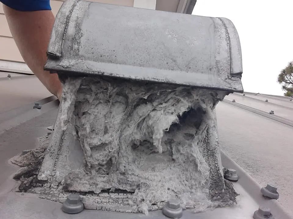 Ventilation pipe on roof covered in thick, white, fibrous material.