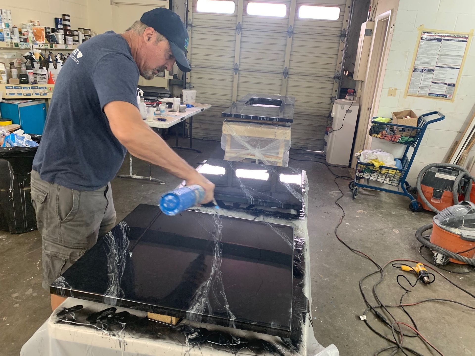 Man spraying a black cabinet with blue paint in a workshop