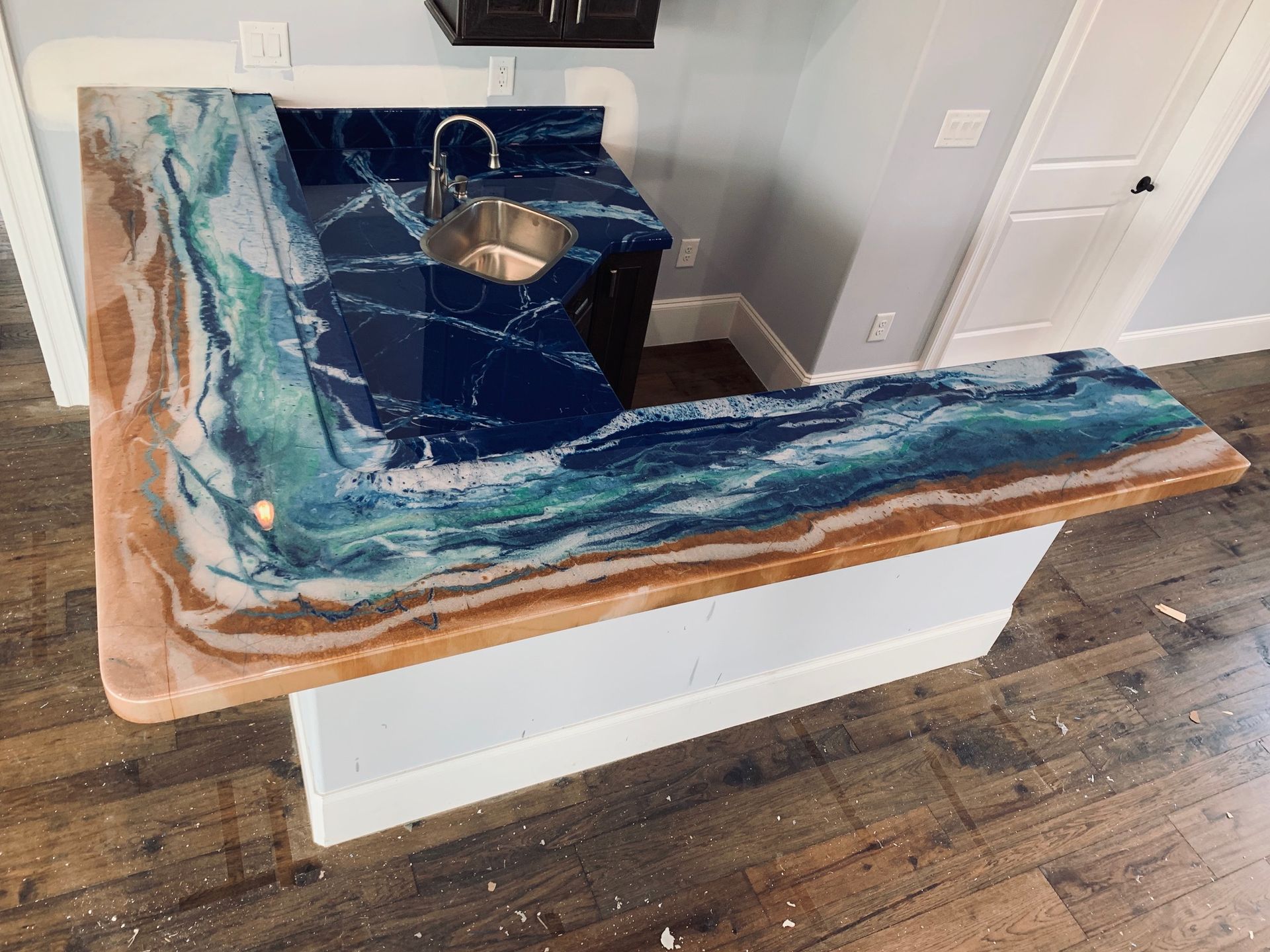 Blue resin and wood L-shaped countertop around a sink in a home kitchen