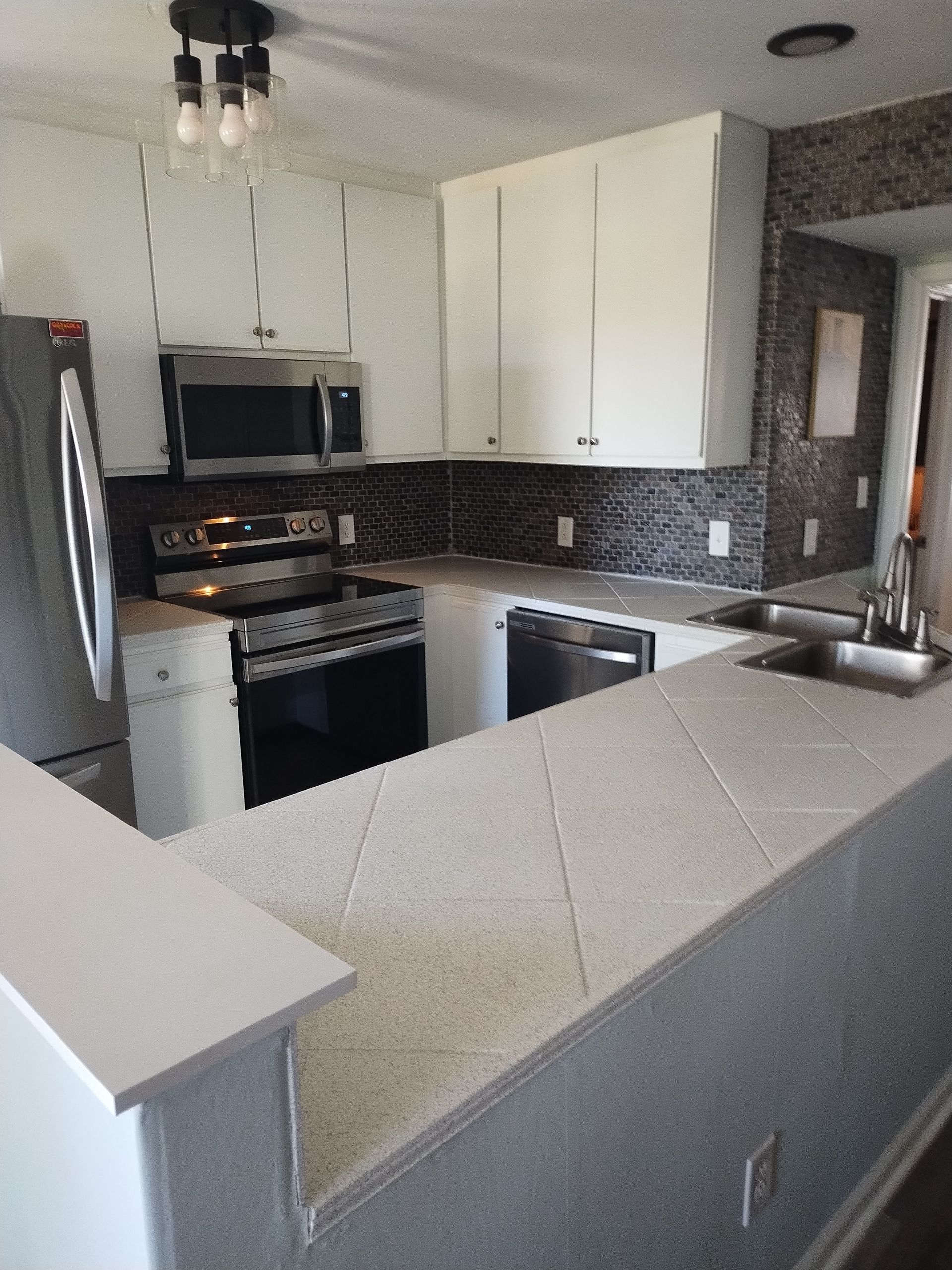 Small kitchen with white cabinets, black appliances, and a gray breakfast bar countertop.
