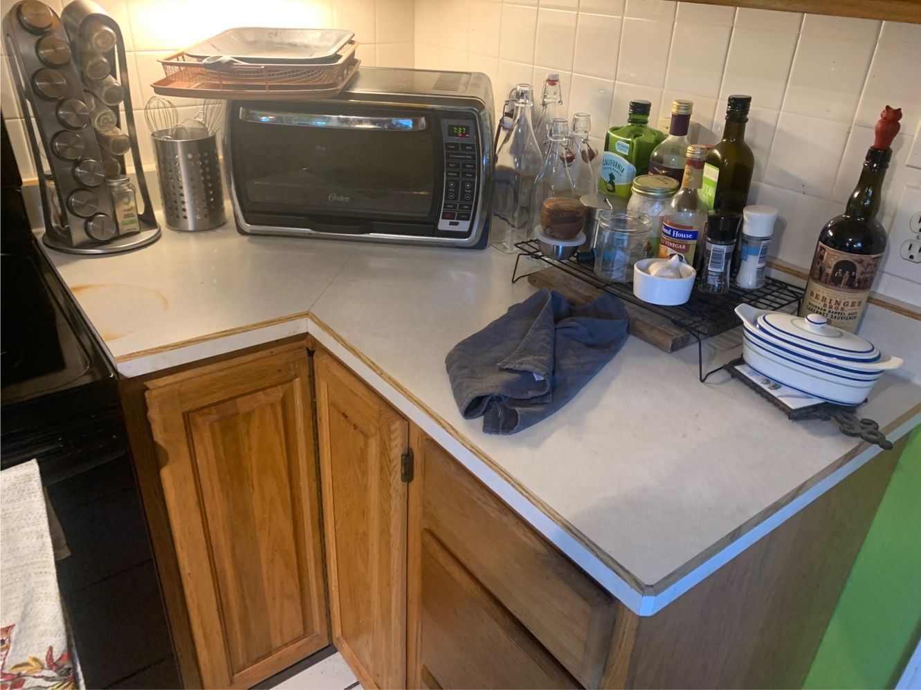Kitchen counter with microwave, bottles, dish rack, and a towel on a corner countertop.