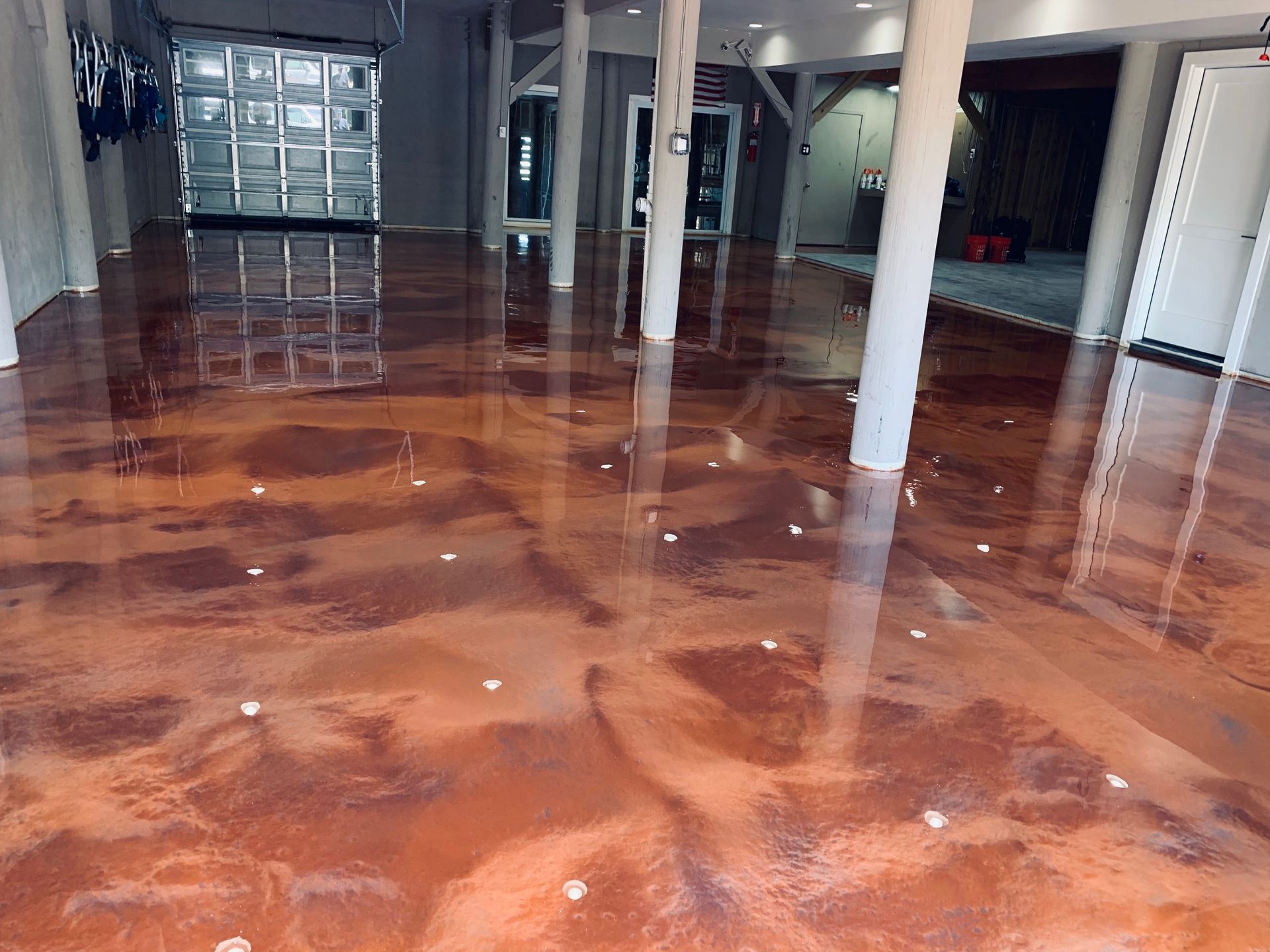 Glossy flooded warehouse floor reflecting ceiling lights and white support columns