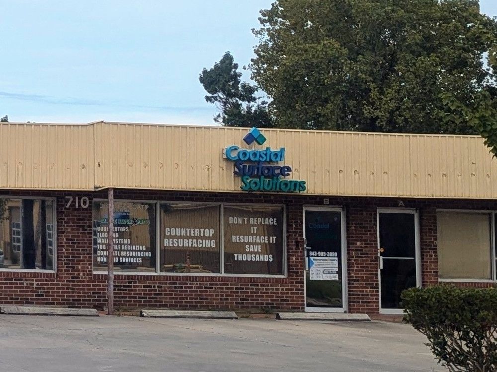 Brick office storefront with blue logo, large windows, and a tan awning.