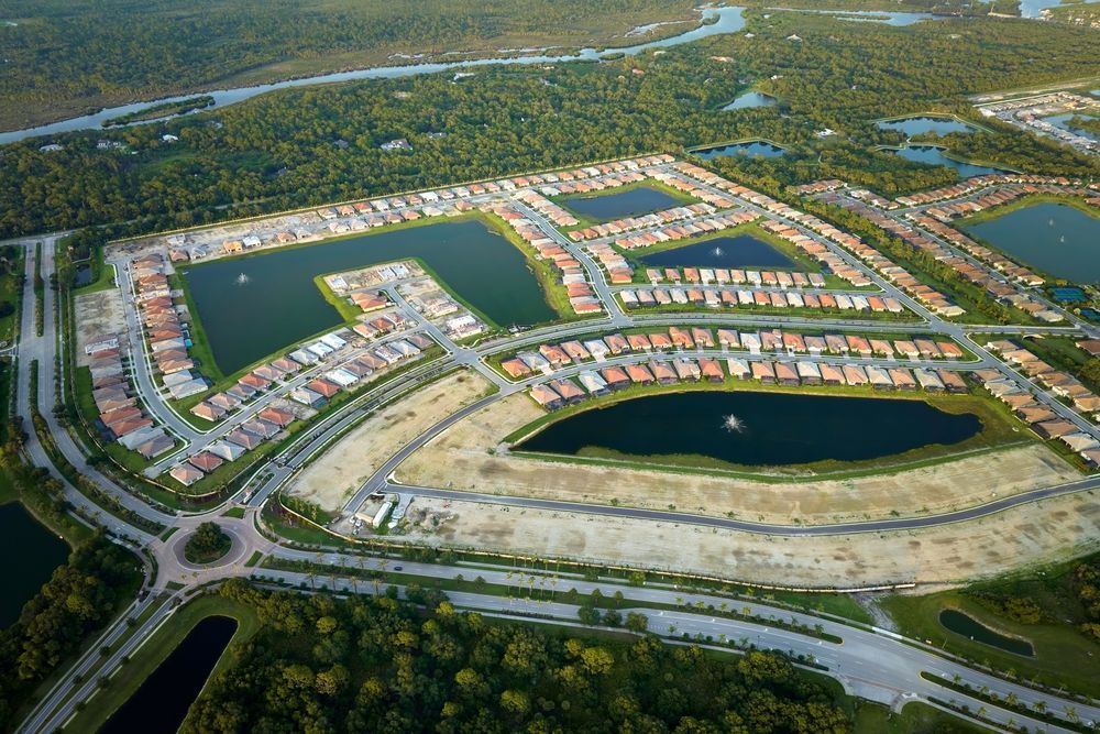 Aerial view of a planned residential development with lakes, roads, and rows of houses amid green landscape