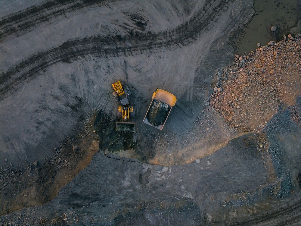 Aerial view of two yellow construction vehicles on a dirt and gravel worksite.