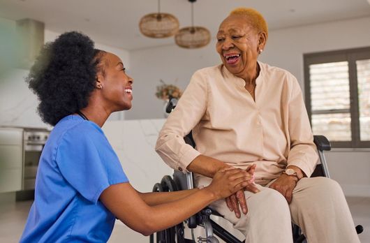 Carer Pushing Senior Woman In Wheelchair Outside Hom