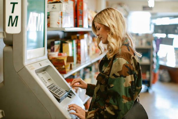 A woman is using an atm machine in a store.