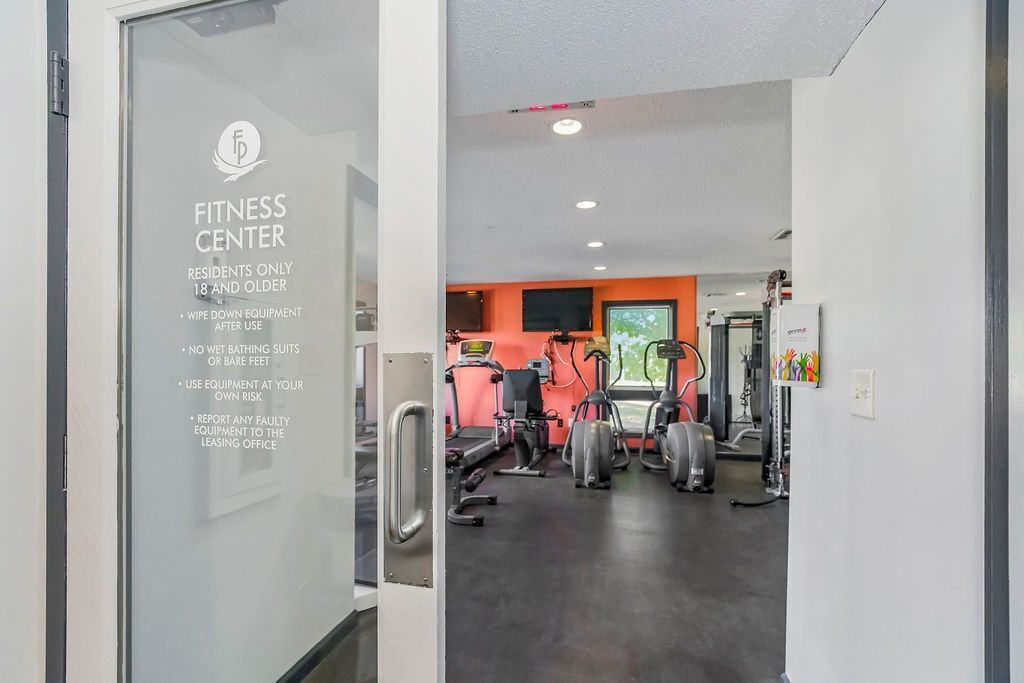 View into a fitness center with gym equipment, through glass doors that read 