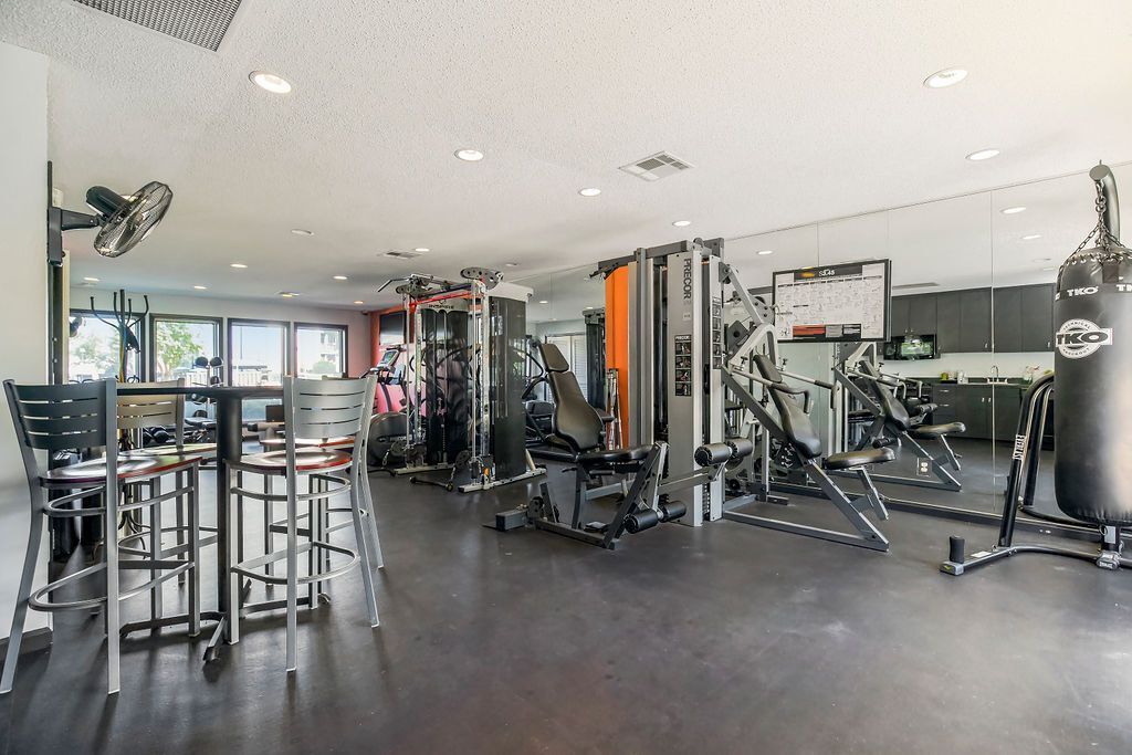 Gym interior with various exercise machines, punching bag, and mirrored wall.