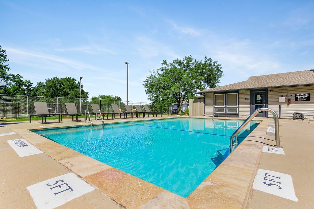 Pool with blue water and chairs on deck, under a blue sky.