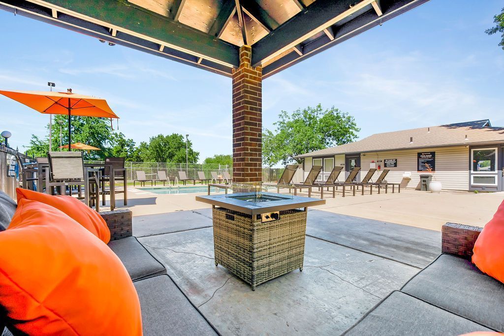 Outdoor patio with seating, fire pit, pool view, and orange accents.