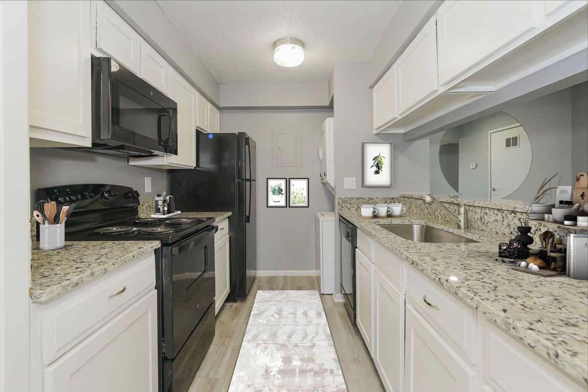 Narrow kitchen with white cabinets, black appliances, and granite countertops.