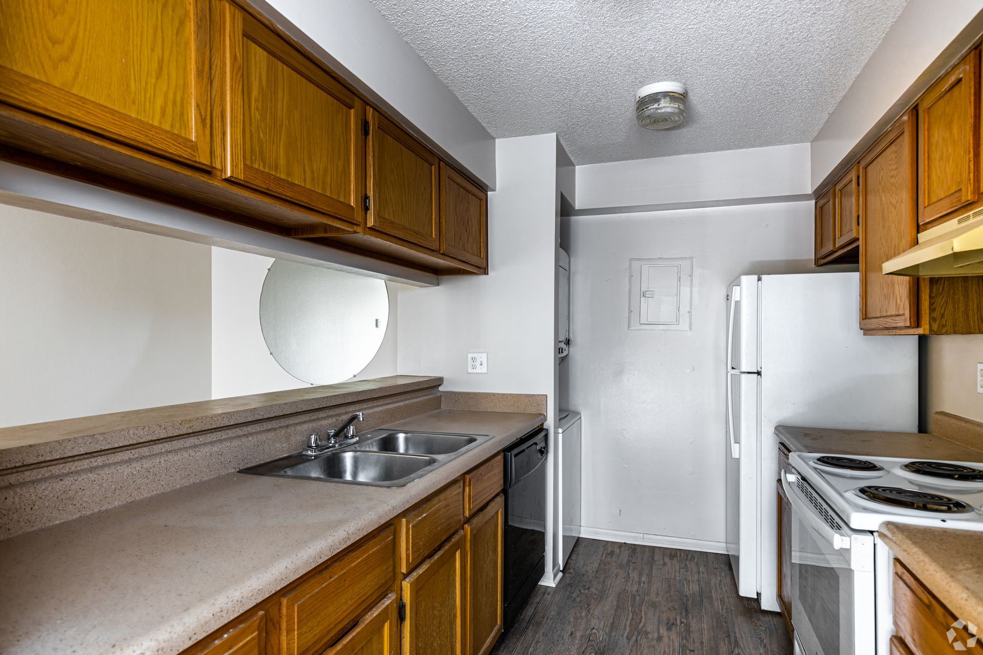 Kitchen with wooden cabinets, light countertops, and white appliances. Includes a sink, dishwasher, and oven.