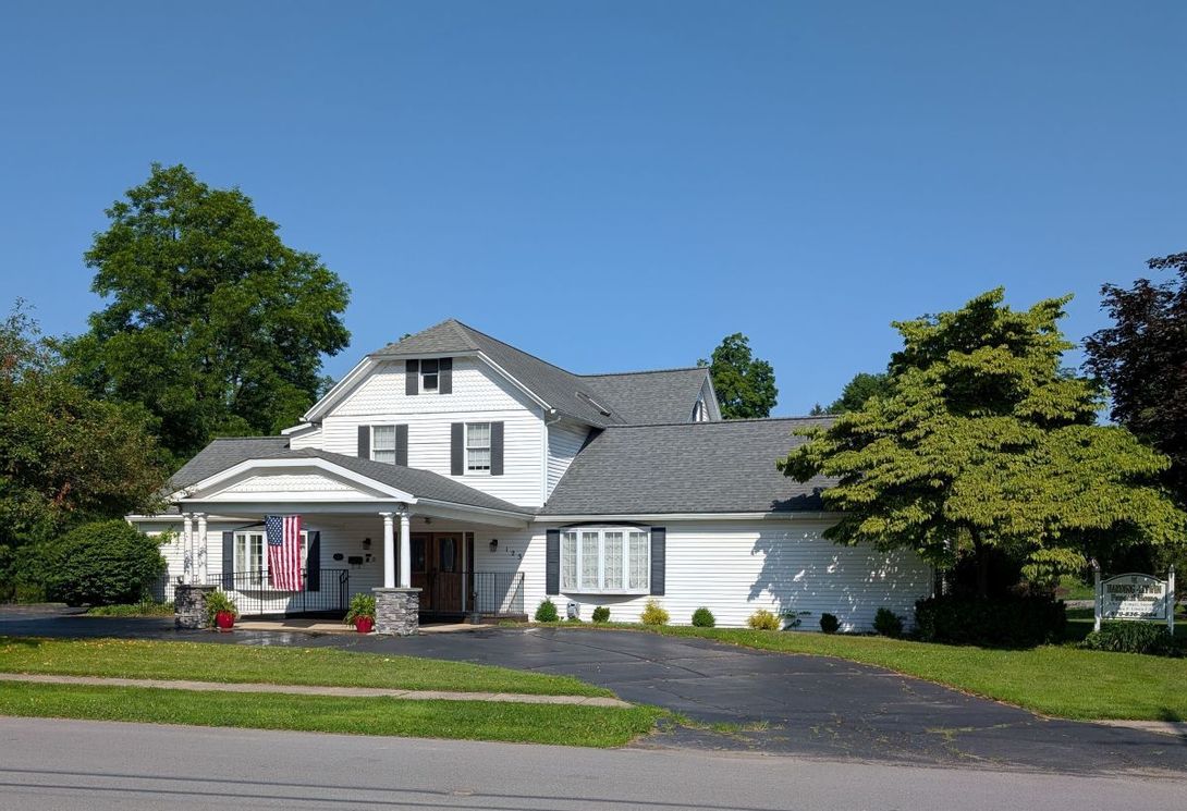 A white house with a gray roof and an american flag on the porch
