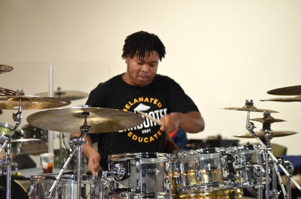A man in a black shirt is playing drums