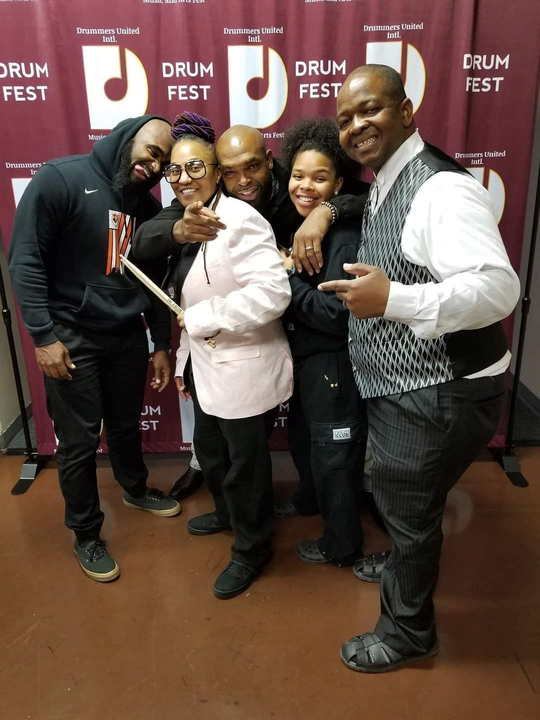 A group of people posing for a picture in front of a drum fest banner